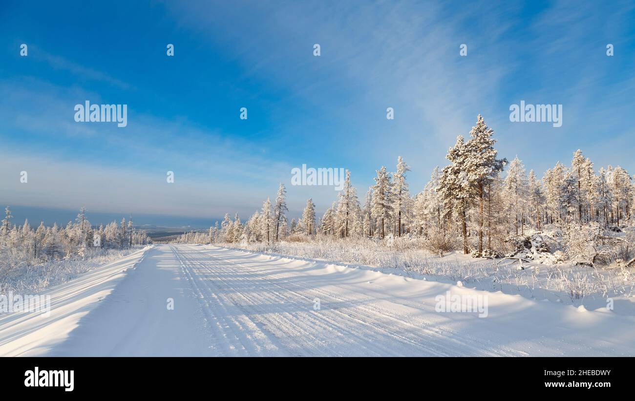 Straße im Winterwald an einem sonnigen Tag. Südjakutien, Russland Stockfoto
