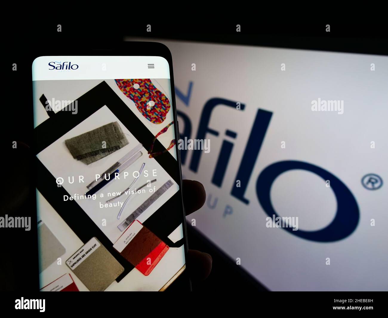 Person, die Smartphone mit Website des italienischen Brillenunternehmens Safilo Group S.p.A. auf dem Bildschirm vor dem Logo hält. Konzentrieren Sie sich auf die Mitte des Telefondisplays. Stockfoto