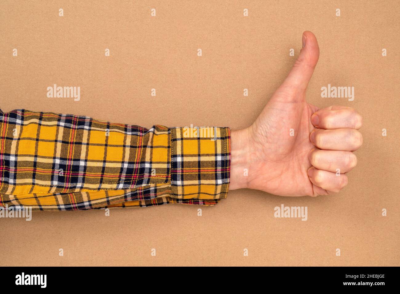 Hand mit Daumen nach oben auf braunem Papierhintergrund. Speicherplatz kopieren. Stockfoto