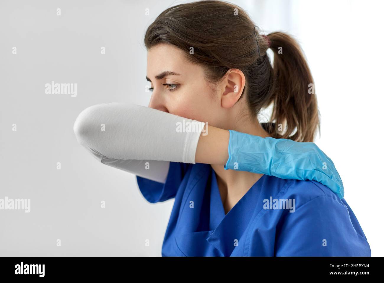 Arzt oder Krankenschwester hustet, wobei der Mund mit dem Ellbogen bedeckt ist Stockfoto