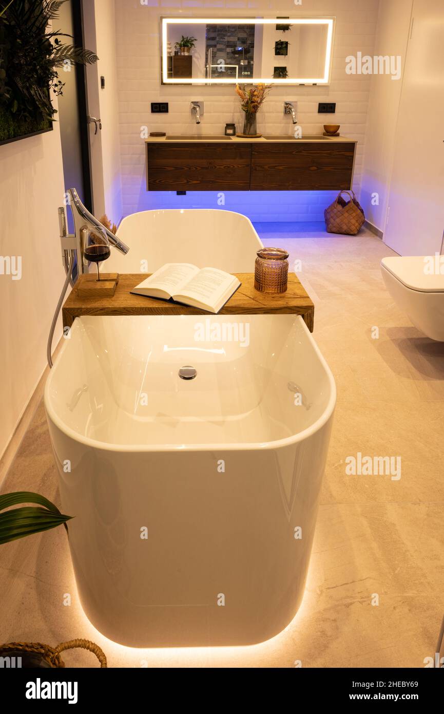 Modernes Badezimmer mit freistehender Badewanne, modernen Armaturen und indirekter LED-Beleuchtung Stockfoto