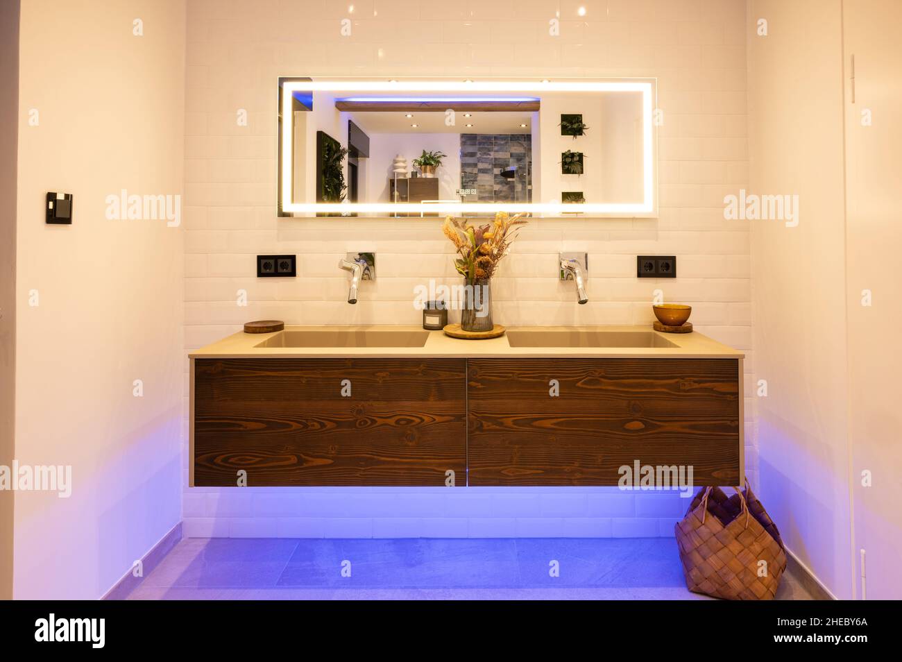 Modernes Doppelwaschbecken aus Eiche und Betonbecken mit modernen Armaturen und beleuchtetem Spiegel im Badezimmer Stockfoto