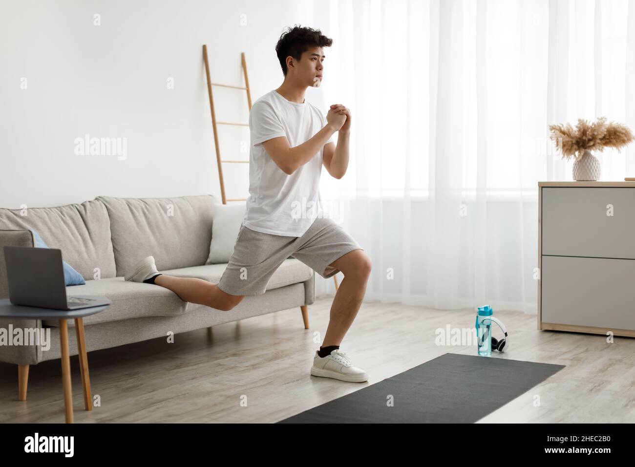 Asian Kerl tun Single Bein Ausfallschritt vor dem Laptop Stockfoto