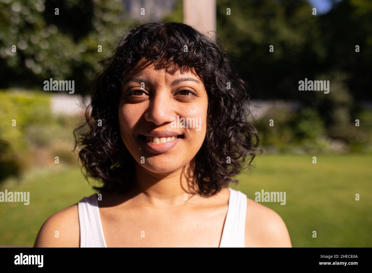 Porträt einer afroamerikanischen Frau, die an einem sonnigen Tag im Garten lächelt Stockfoto