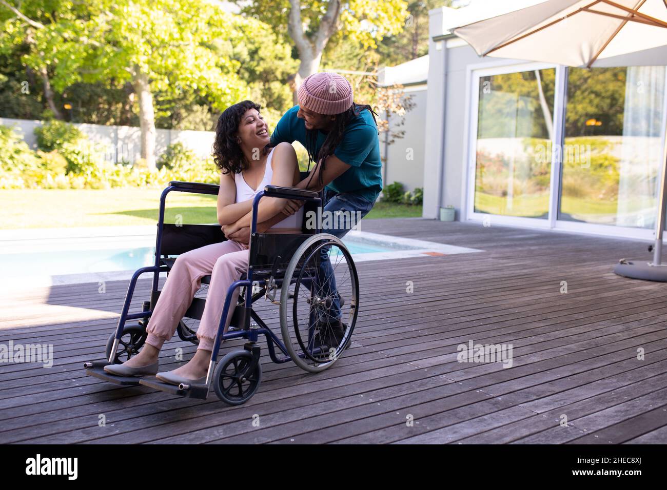 afroamerikanischer Mann umarmte seine behinderte Frau im Rollstuhl und lächelte im Freien Stockfoto
