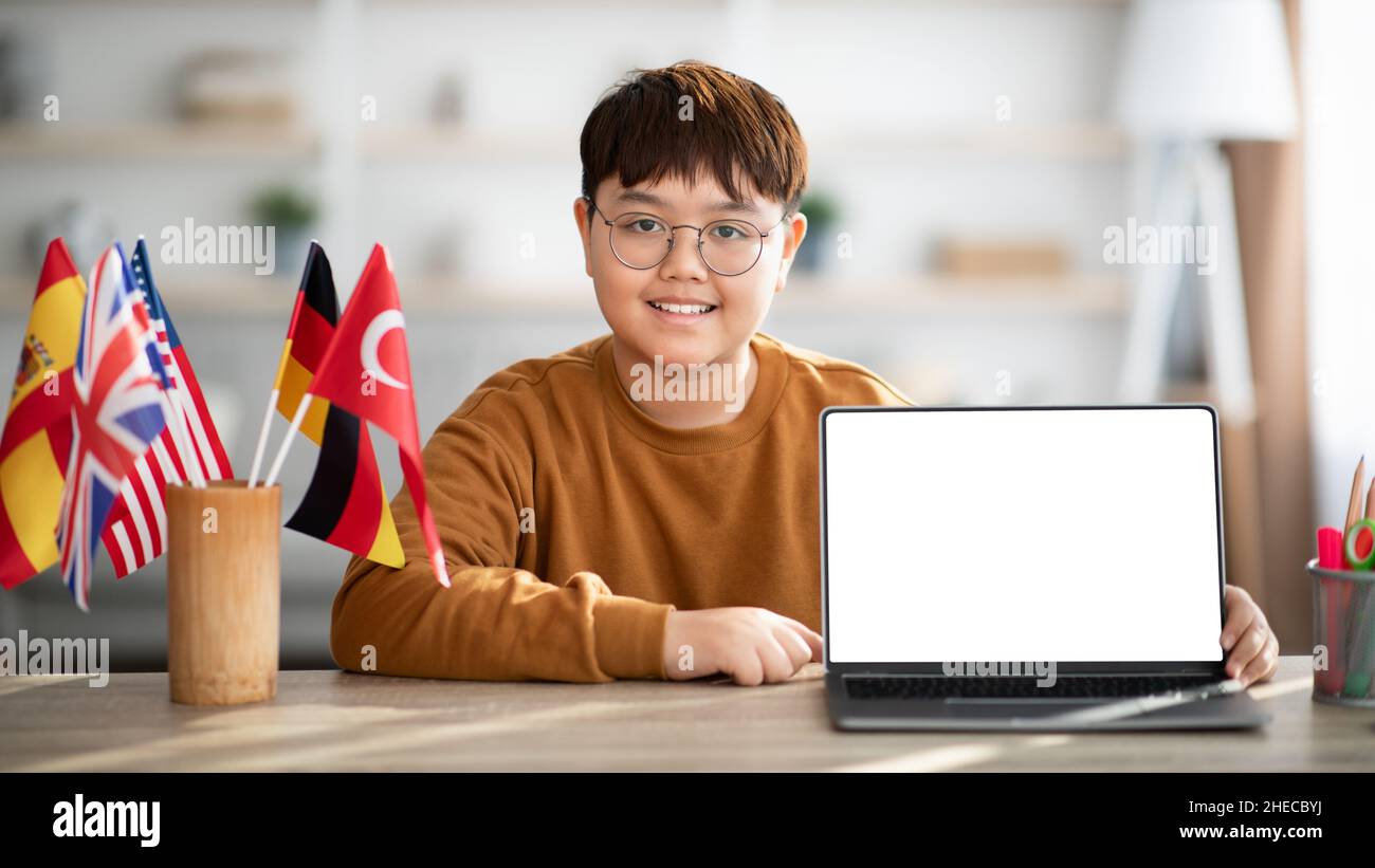 Glücklicher chinesischer Teenager Junge zeigt Laptop mit leerem Bildschirm Stockfoto