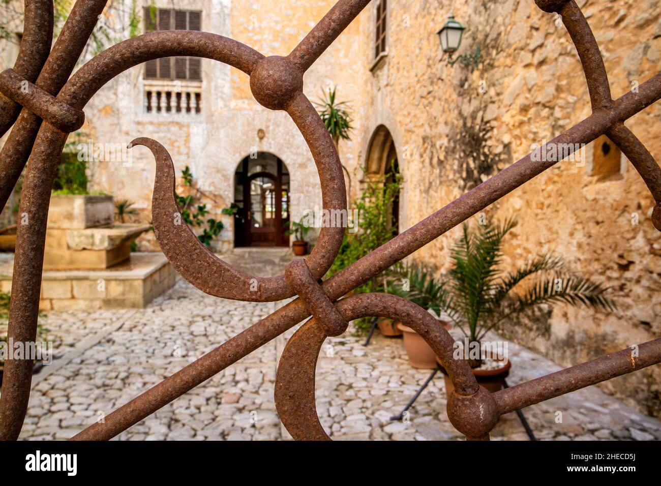 Ornamentales Eisentor mit Blick auf einen Innenhof eines mediterranen Stadthauses in Santanyí, Mallorca, Mallorca, Balearen, Spanien Stockfoto