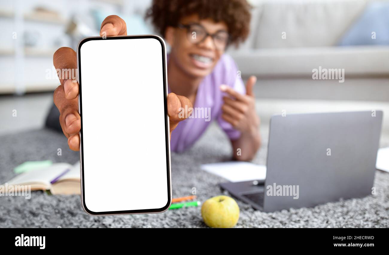 Bildungs-App Schwarz Teen Guy Zeigt Blank Smartphone Während Studie Zu Hause Stockfoto