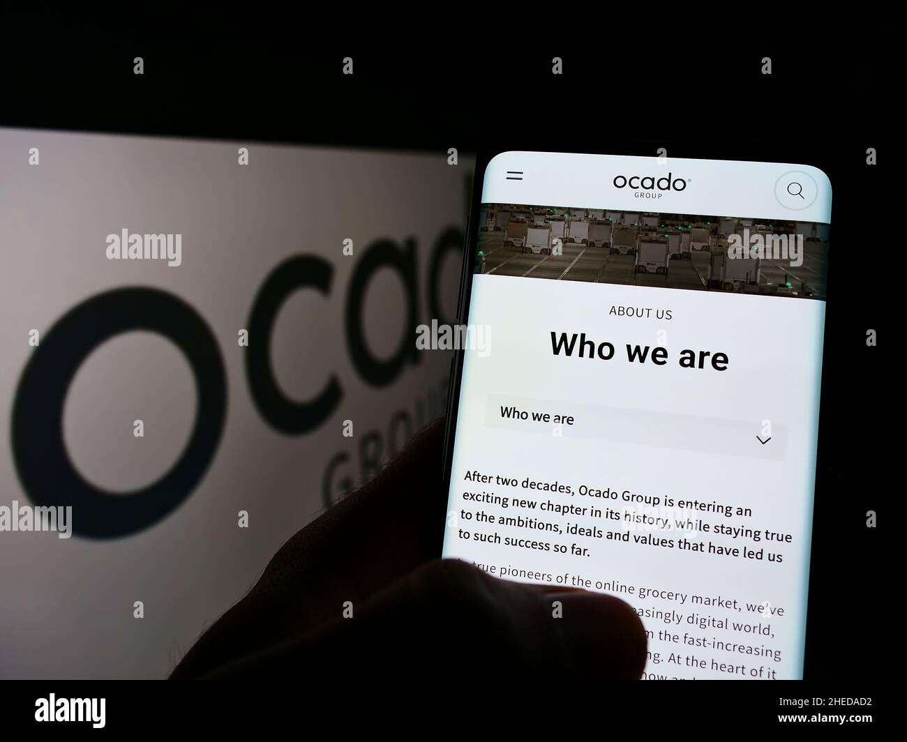 Person, die ein Smartphone mit einer Webseite des britischen Einzelhandelsunternehmens Ocado Group plc auf dem Bildschirm vor dem Logo hält. Konzentrieren Sie sich auf die Mitte des Telefondisplays. Stockfoto