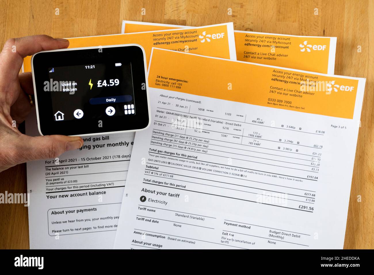 Ein intelligenter Zähler zeigt den täglichen Stromverbrauch über einem Haufen von Gas- und Stromrechnungen an. Stockfoto