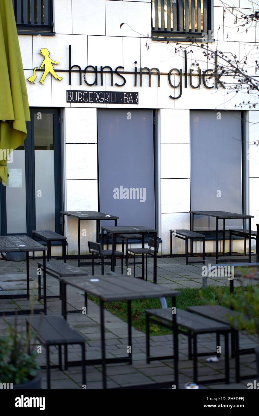 Stuttgart, 31. Dezember 2021: Burger-Grillbar von außen. Leere Tische und Bänke mit gefaltetem Sonnenschirm. Der Name stammt aus einem Märchen. Stockfoto