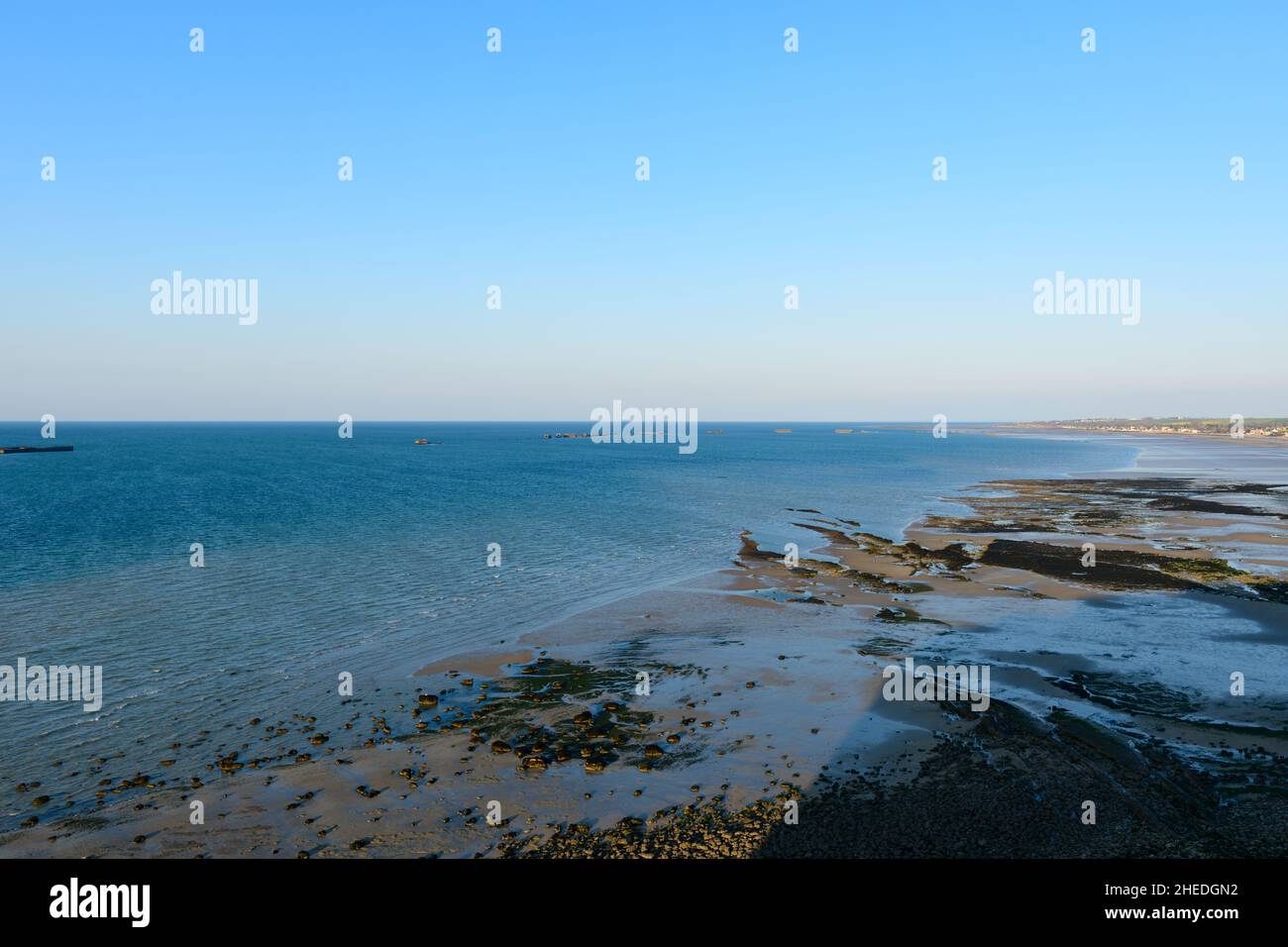 Dieses Landschaftsfoto wurde im Sommer in Europa, Frankreich und der Normandie aufgenommen. Wir können den Strand von Arromanches bei Ebbe und unter der Sonne sehen Stockfoto