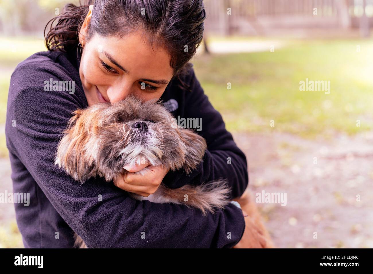 Nette junge Frau küsst und umarmt ihren kleinen Welpen. Liebe zwischen Besitzer und Hund. Außenfoto im Park, selektiver Fokus. Lifestyle-Konzept Stockfoto