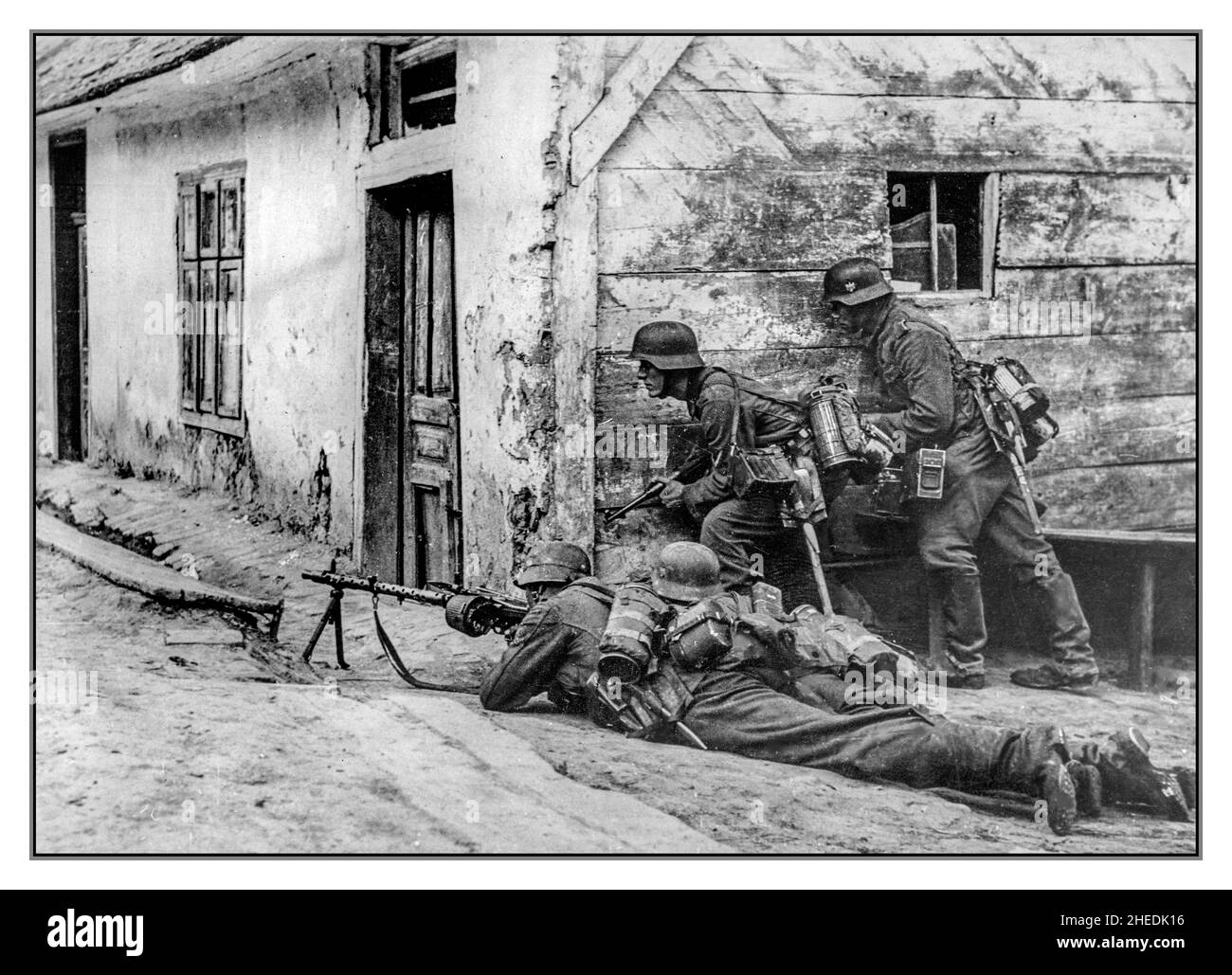 Operation Barbarossa WW2 Straßenkämpfe in einem Dorf an der Ostfront. Vier Nazi-deutsche Soldaten verstecken sich hinter der Ecke des Hauses. Nazi-deutscher Soldat mit MG-34-Maschinengewehr im Vordergrund. Stockfoto