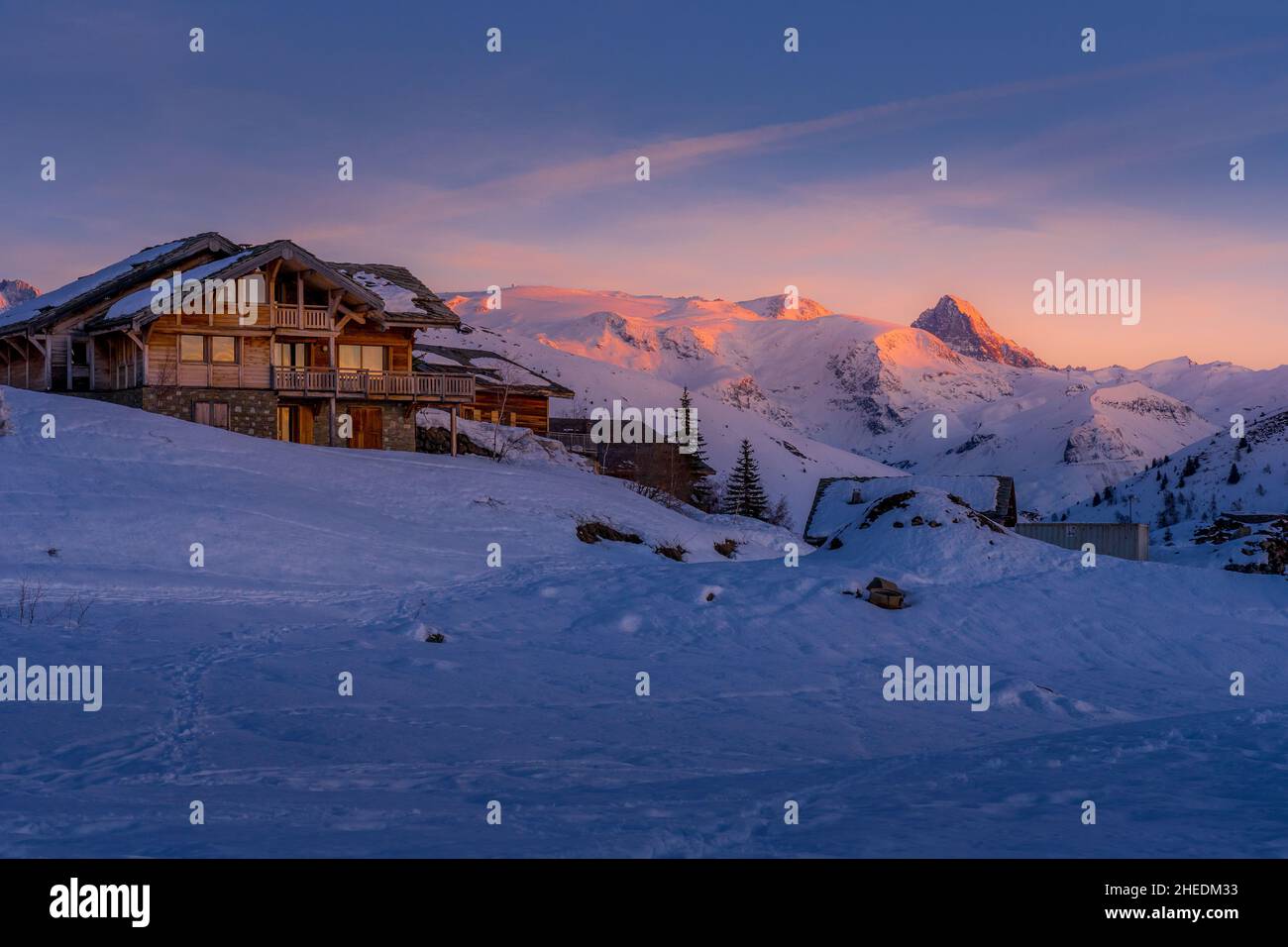 Alpe d'Huez, Frankreich - 30.12.2021: Alpiner Berg-Winterort mit Holzchalet am späten Abend. Typische französische Winterlandschaft. Hoch Stockfoto