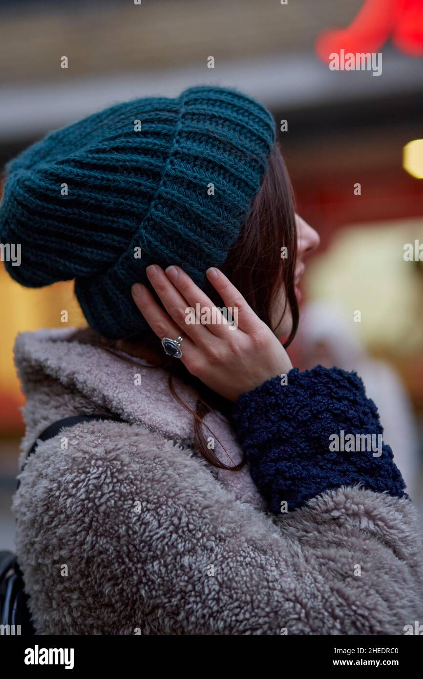 Nahaufnahme eines Frauenportraits in der Abendstraße. Modische Winter-Freizeitkleidung. Lichter der Stadt. Festliche Stadt. Details von Kleidung, Accessoires. Stockfoto