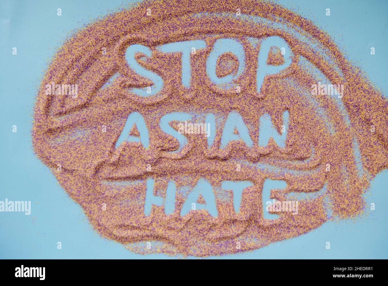 Stoppen Sie asiatischen Hass Text handgeschrieben auf bunten Sand. Tatsächliches Problem. Hochwertige Fotos Stockfoto