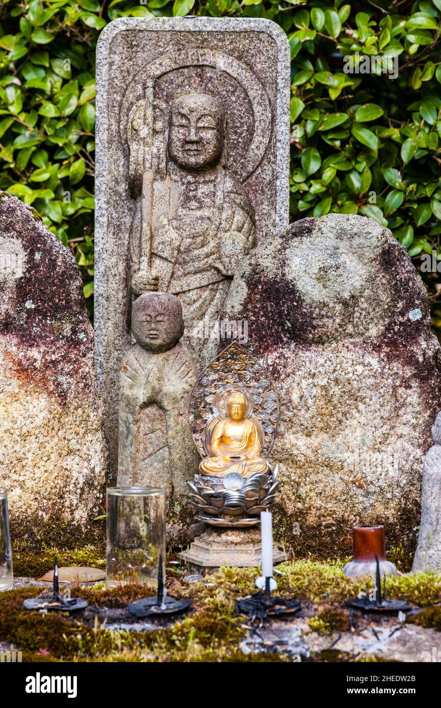 Kleine buddha-Statue mit Münzopfern zu Füßen, dahinter zwei größere Jizo-Statuen, im Saisho-in Garten, Nanzen Tempel. Kyoto. Stockfoto