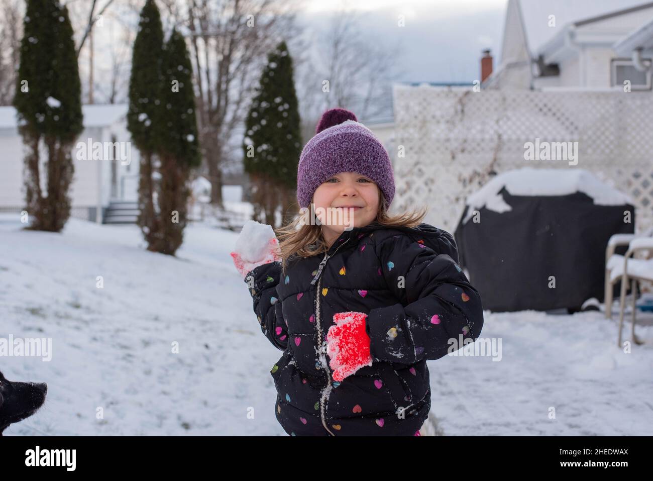 Ein kleines Kind wirft im Winter einen Schneeball auf die Kamera zu. Stockfoto