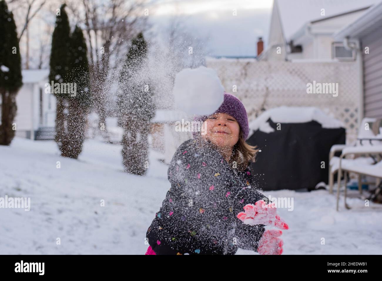 Ein kleines Kind wirft im Winter einen Schneeball auf die Kamera zu. Stockfoto