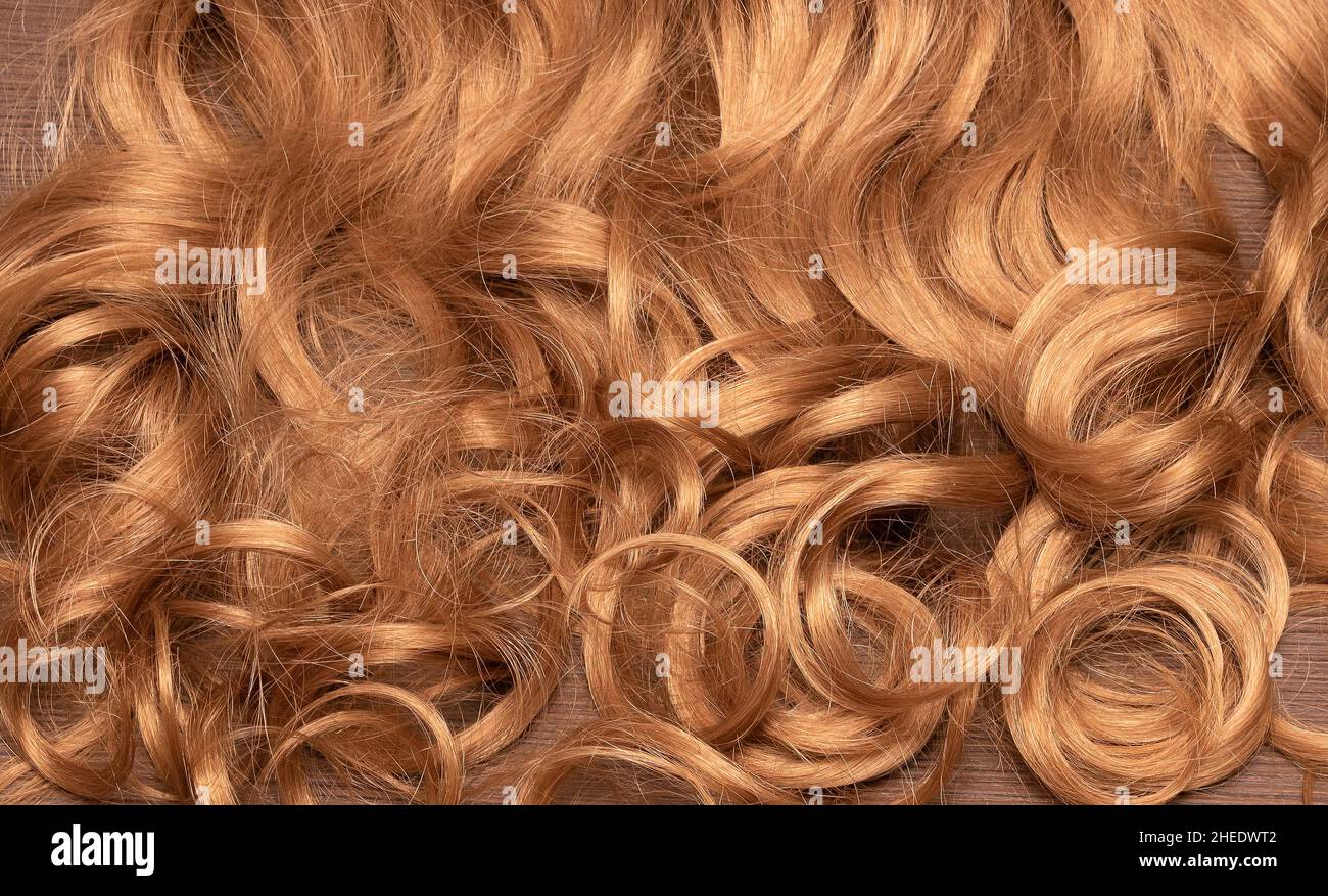 Goldfarbenes, dunkelblondes Haar mit lockigen Wellen, Textur im Hintergrund Stockfoto