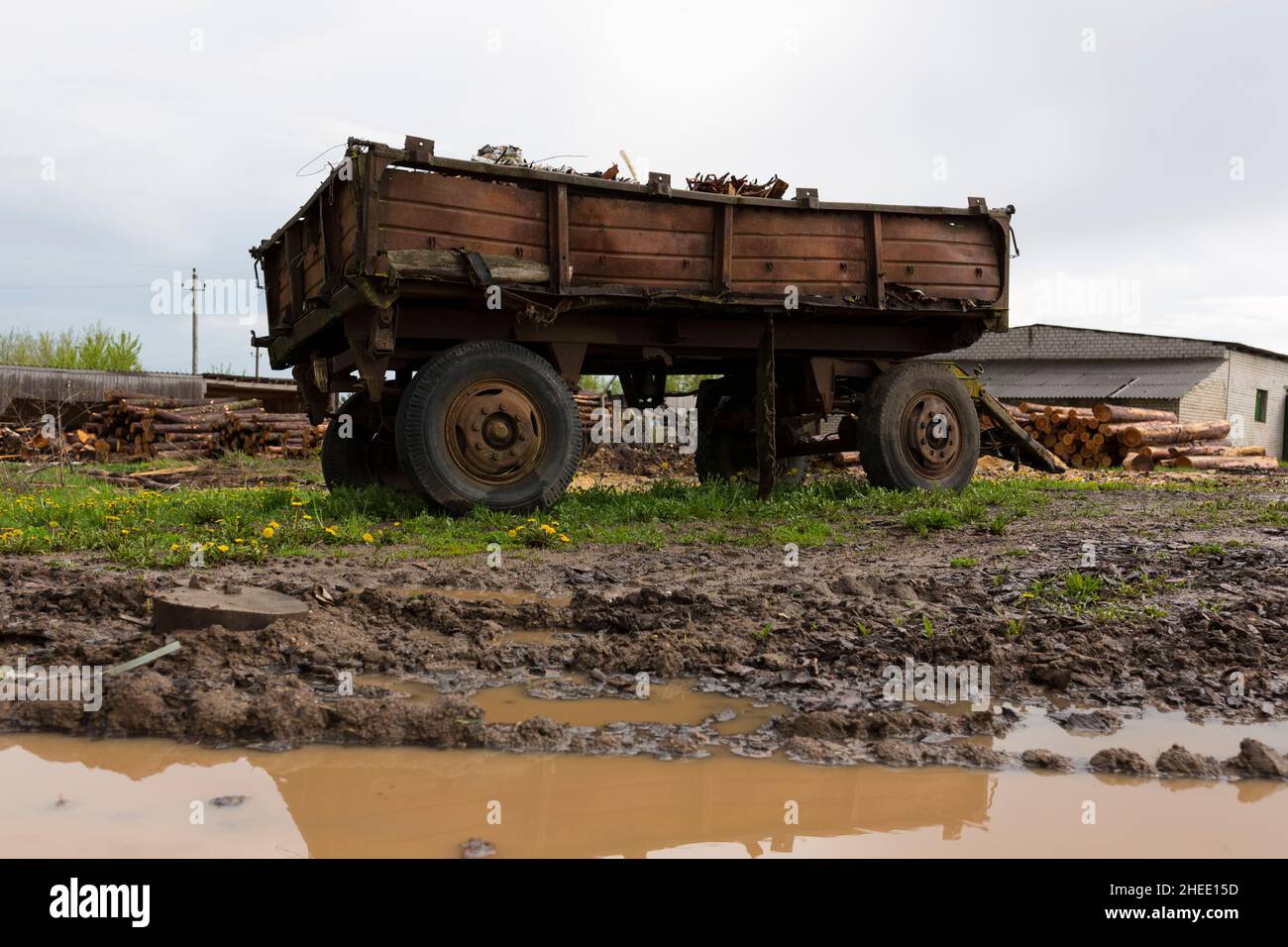 Alte verlassene rostigen Traktoranhänger. Steht auf einem grünen Rasen in einer schlammigen Pfütze. Stockfoto