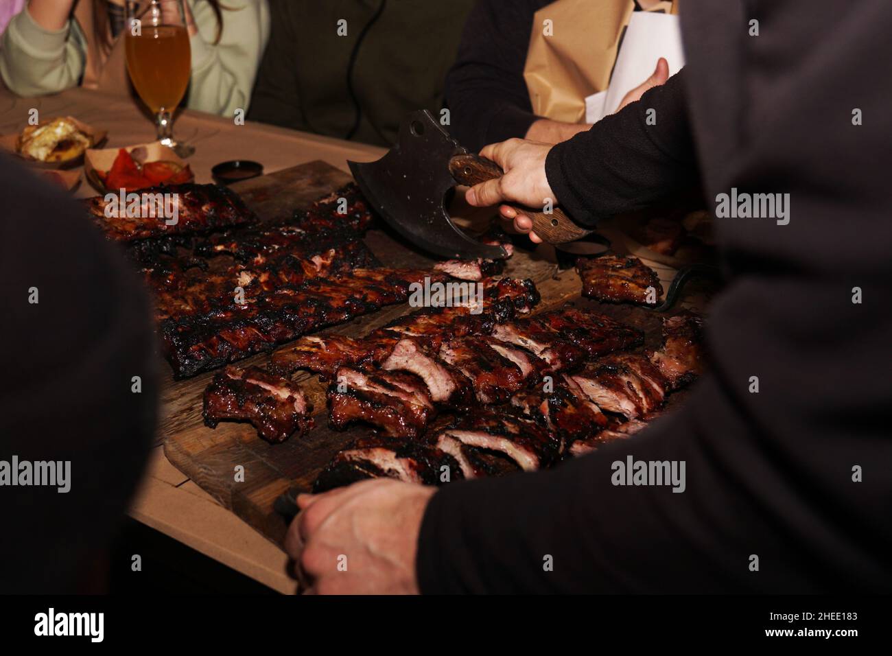 Der Kellner zerkleinert saftige Grillrippchen, wenn er den Restaurantkunden serviert. Fleisch-Restaurant in Lviv Stockfoto
