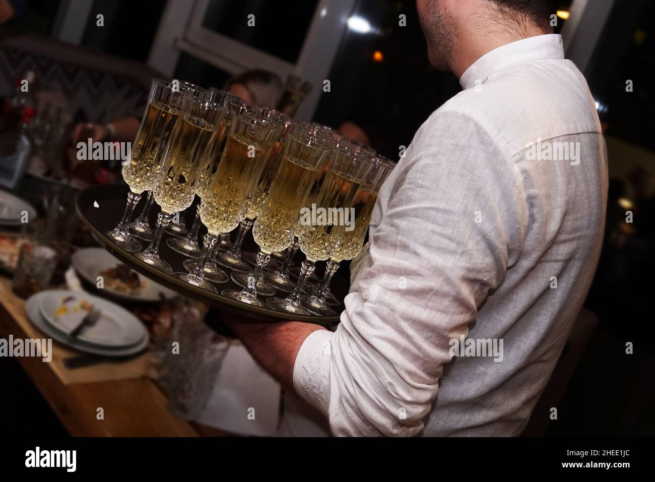 Ein Kellner mit Gläsern mit Champagner serviert auf einer Tablette. Viele Gläser für ein großes Unternehmen Stockfoto