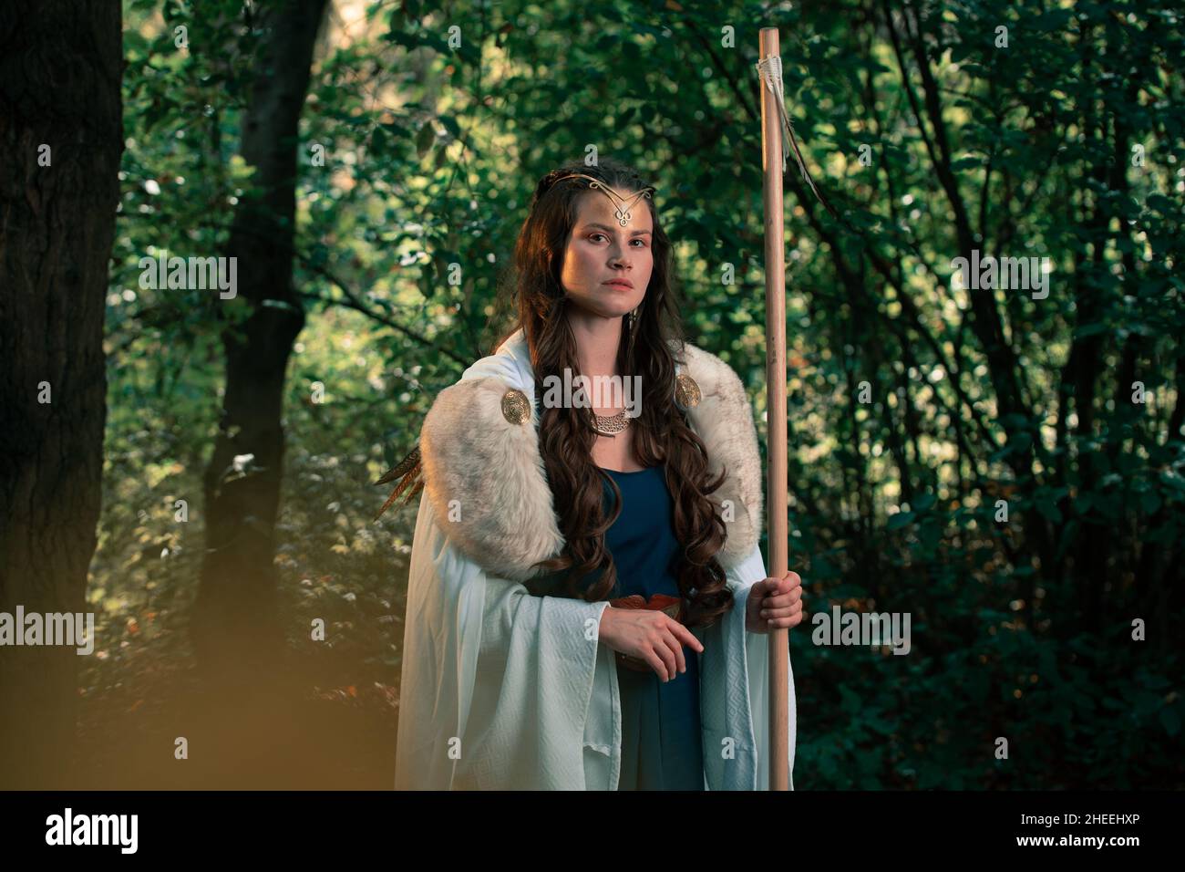 Seriöse Frau in Kleid und Pelzmantel stehen in Wäldern für den mittelalterlichen Wiederaufbau und Blick auf die Kamera Stockfoto