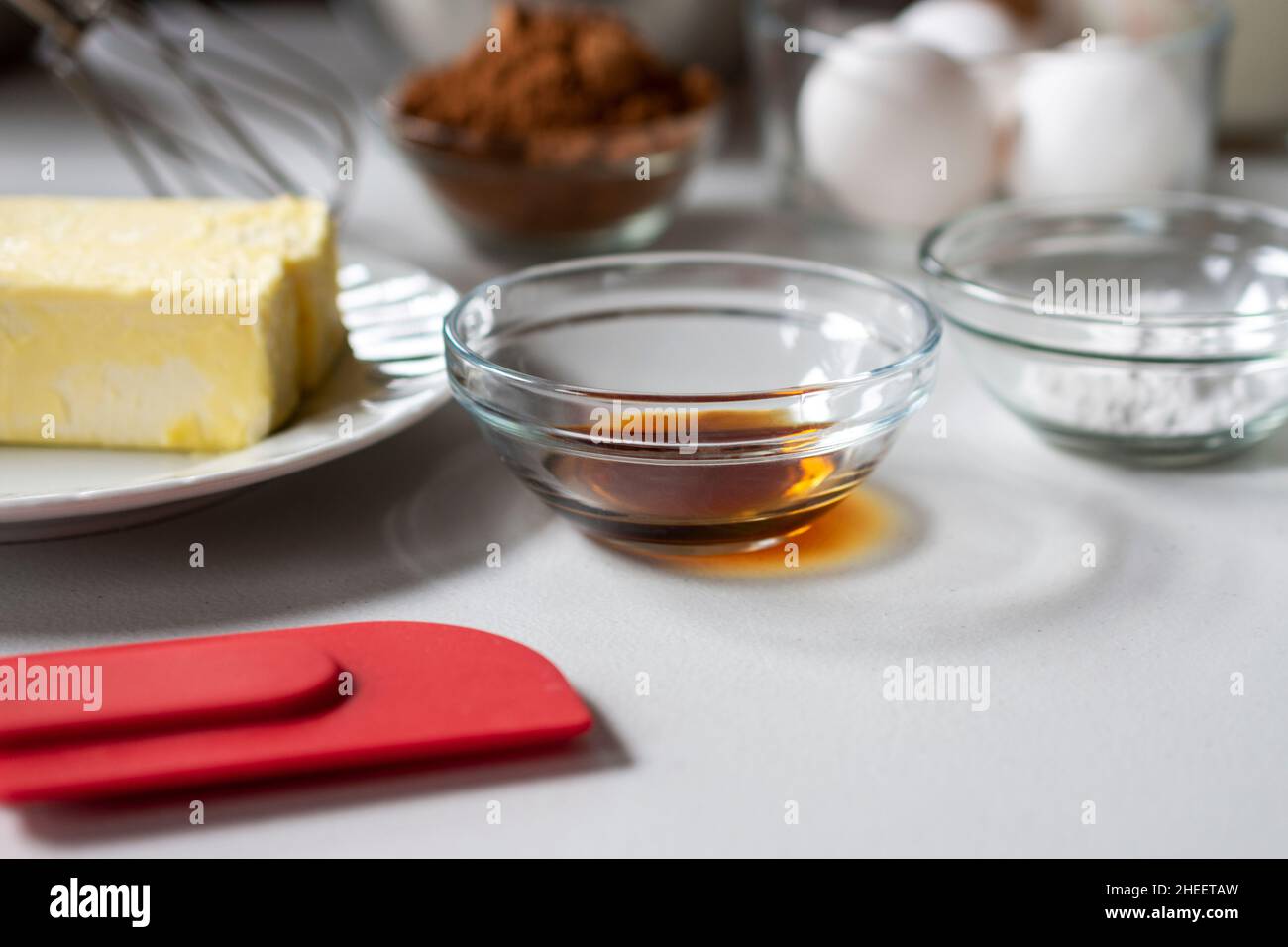 Seitenansicht der Backzutaten. Zu den Zutaten gehören: Ei, Butter, Vanille, Kakao und Backpulver. Stockfoto