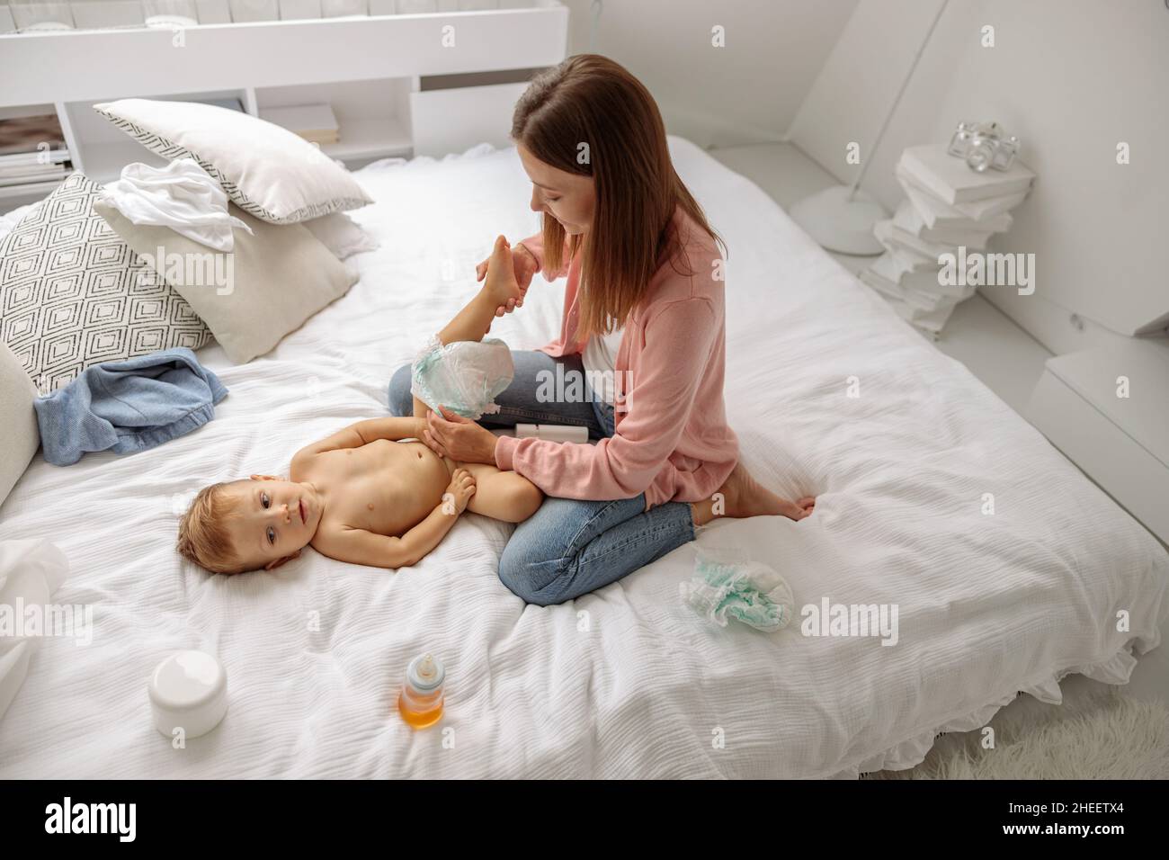 Glückliche Mutter, die im Schlafzimmer die Windel zu ihrem Baby wechselt Stockfoto
