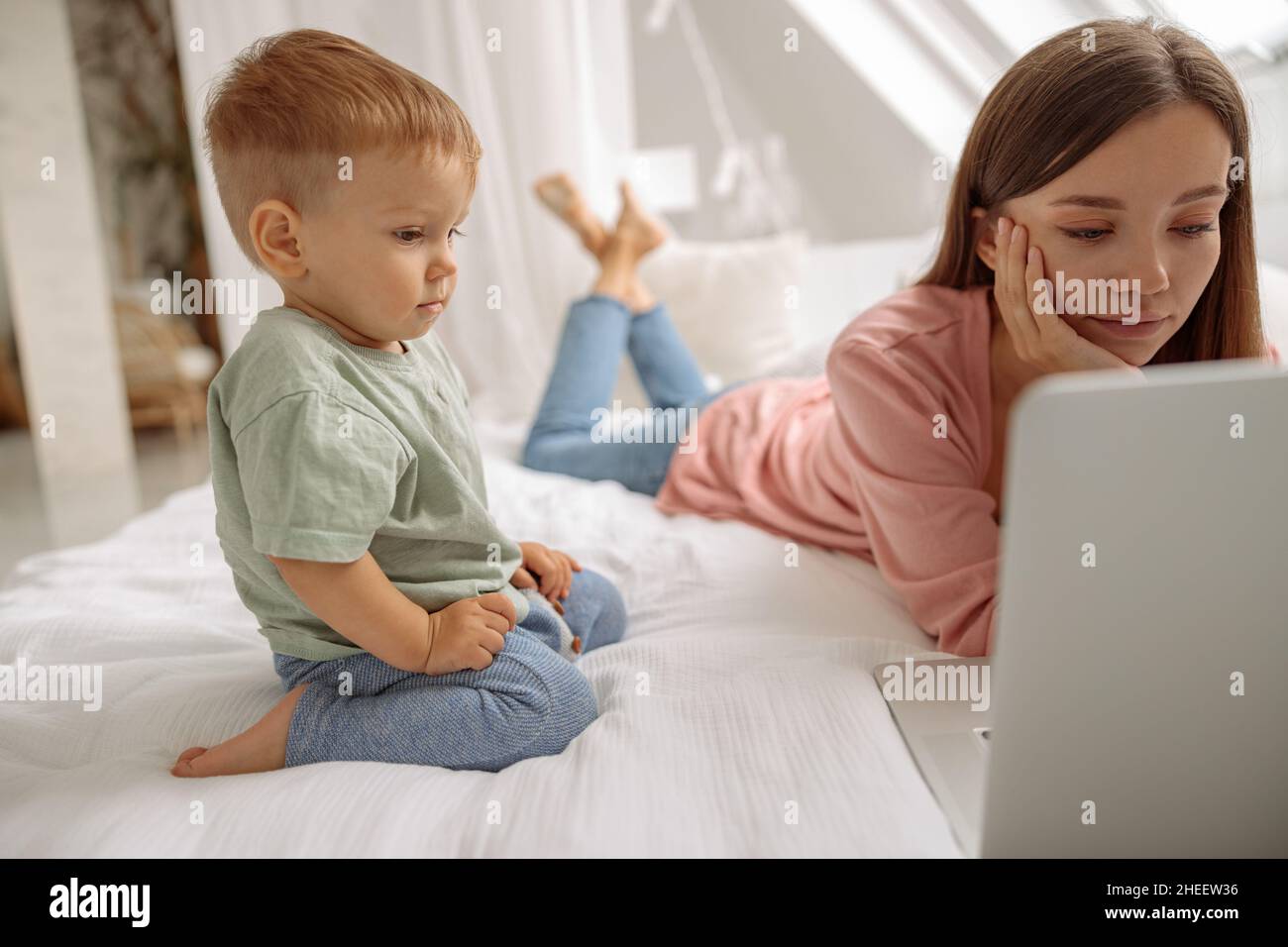 Niedliches Baby, das zu Hause auf den Laptop-Bildschirm schaut Stockfoto