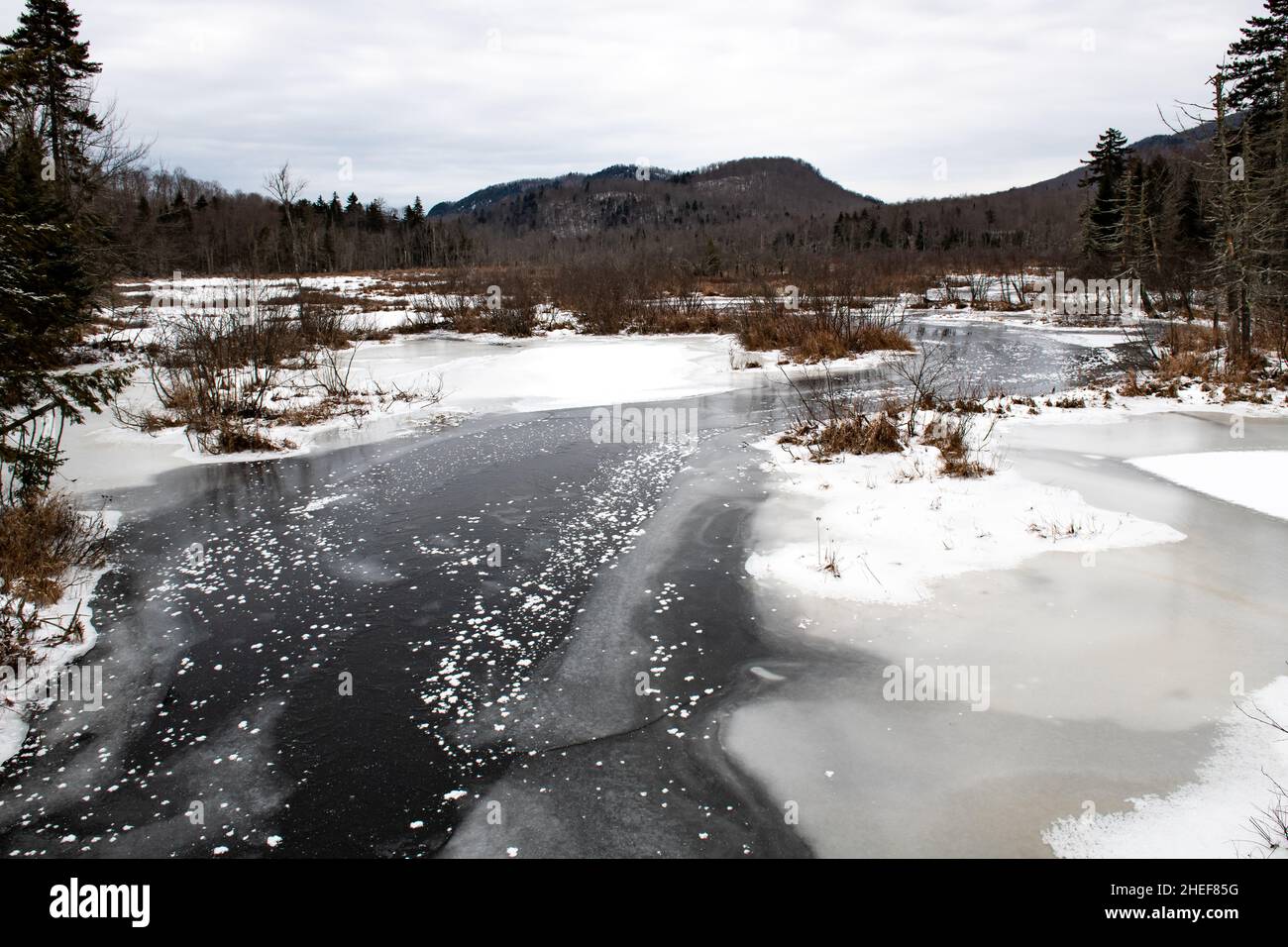 Ein Blick auf den Kunjamuk River in den Adirondack Mountains im Winter mit Schnee und Eis auf dem Wasser. Stockfoto