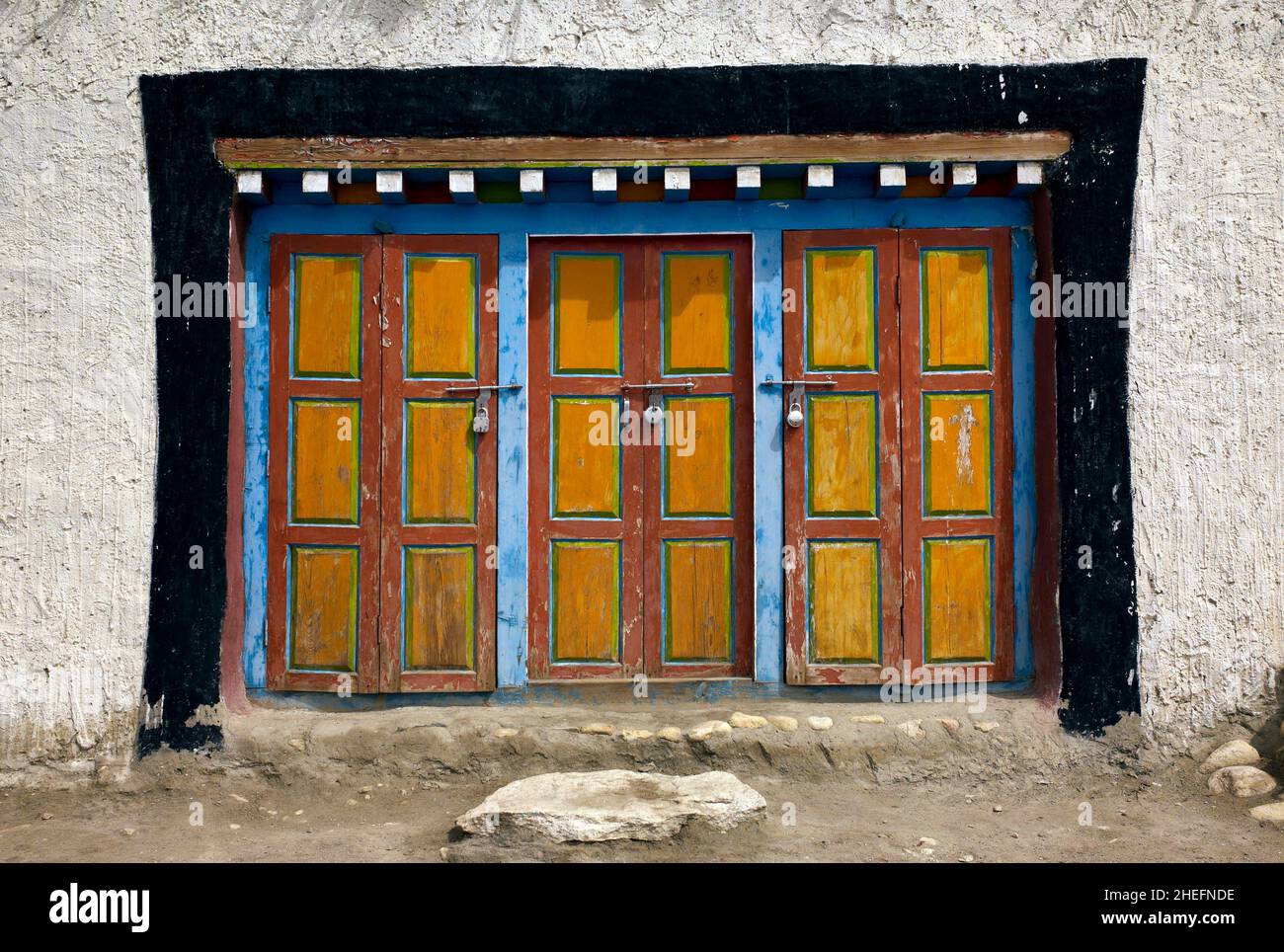 Farbfoto von drei farbenfrohen tibetischen Türen eines weiß getünchten Steingebäudes, Zsarang, Himalaya, Nepal, Asien, 2011. Stockfoto