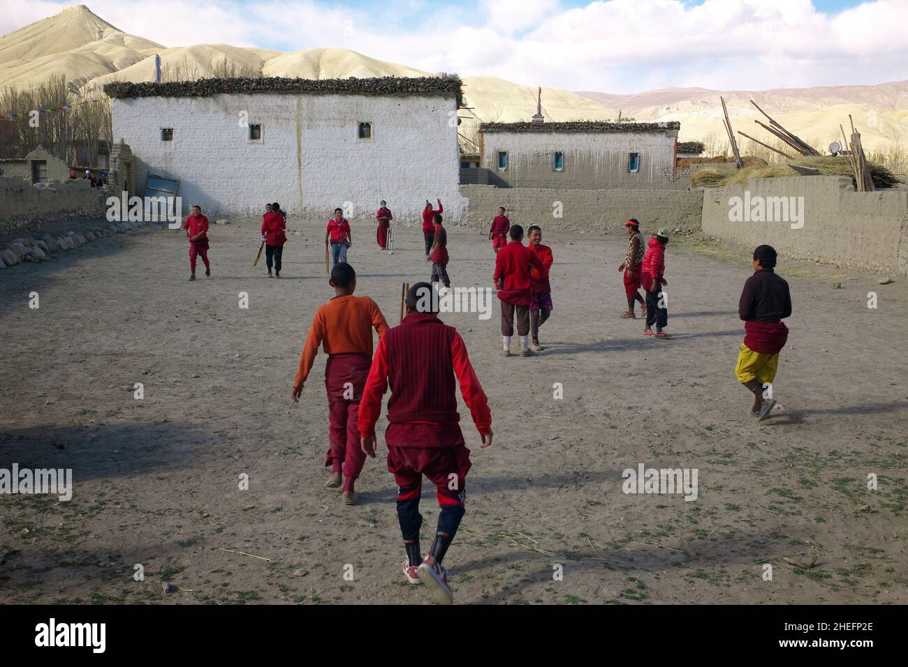 Farbfoto von buddhistischen Mönchen, die ein Cricket-Spiel auf einem unbefestigten Innenhof spielen, Lo Manthang, Mustang, Nepal, Asien, 2011. Stockfoto