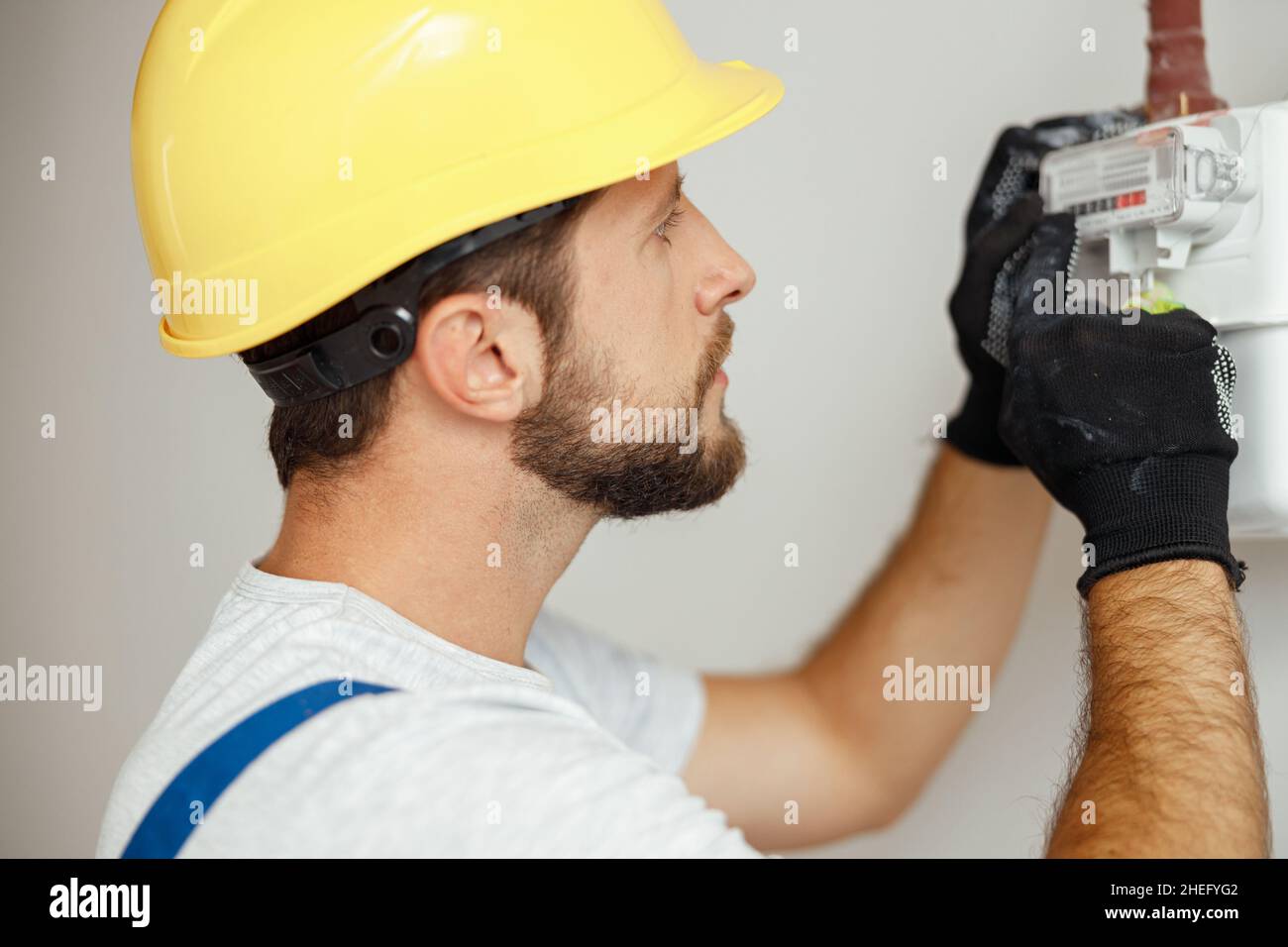 Nahaufnahme eines ernsthaften Heizungsmonteur, der den Gasverbrauch an der Gasleitung und am Zählerstab überprüft Stockfoto