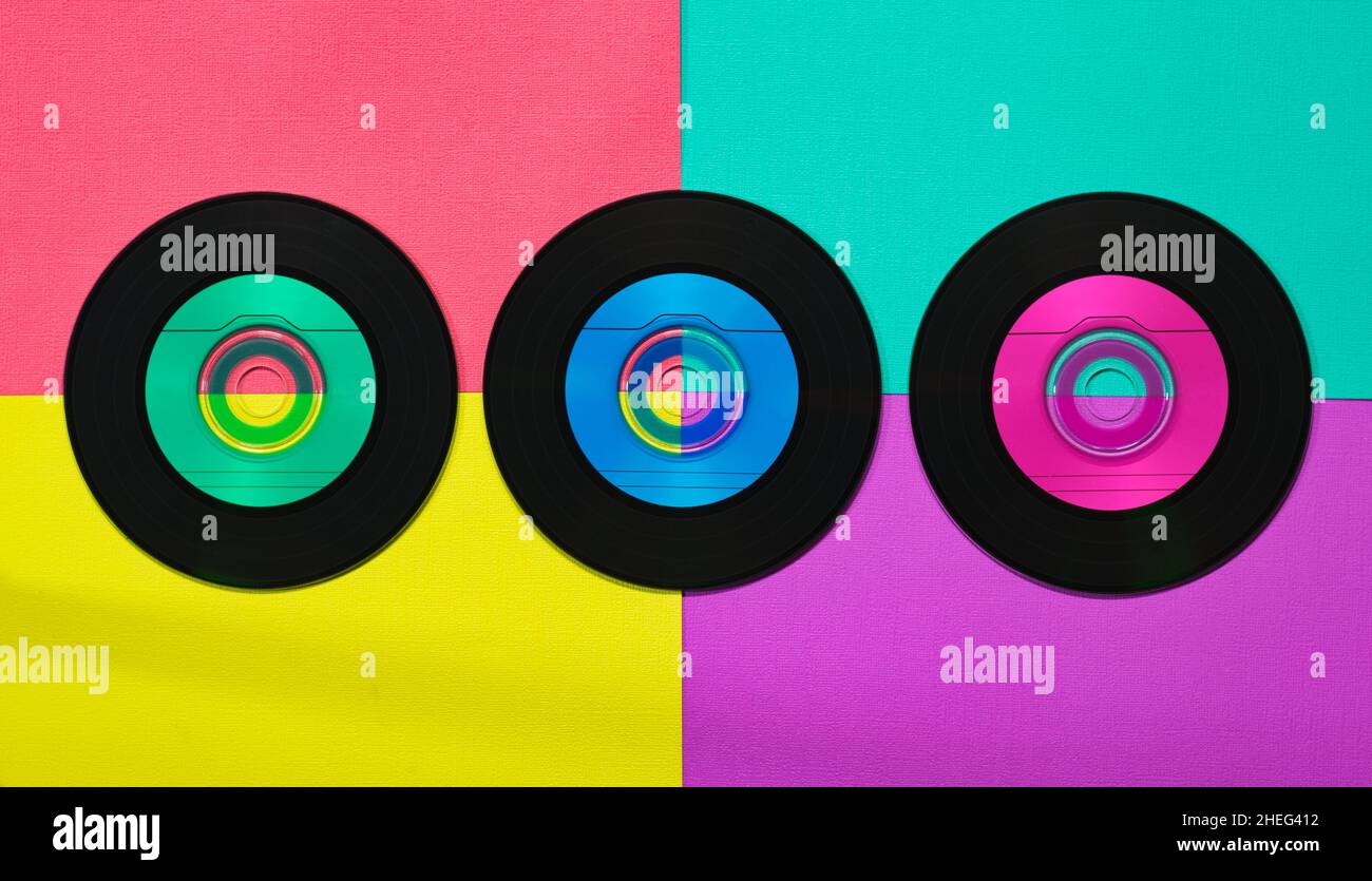 Drei Vinyl-CDs im flachen Lay-Format auf einem bunten, lebendigen Retro-Hintergrund. Stockfoto