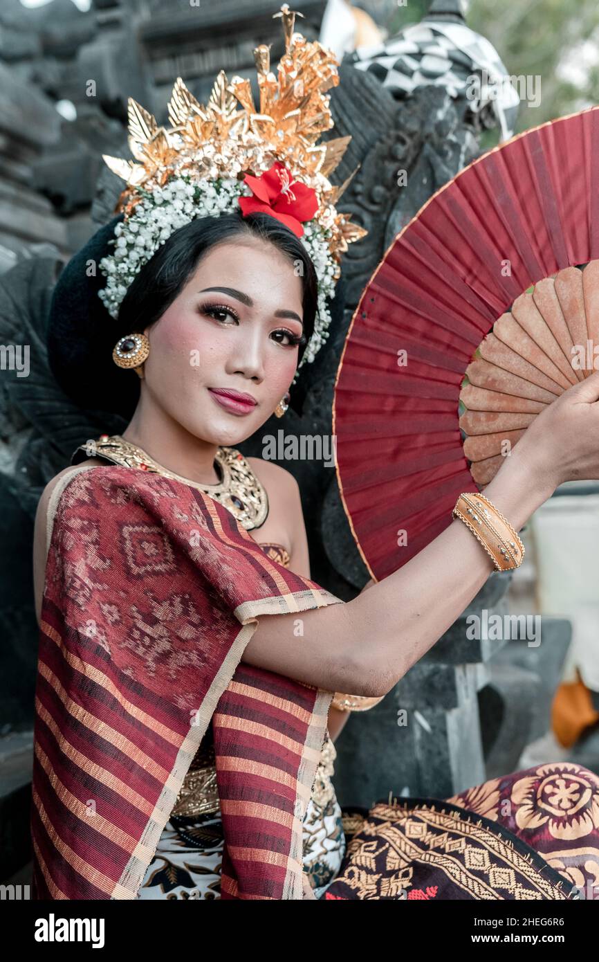 Junge einheimische balinesische Mädchen mit einem traditionellen Kleid stehen mit Klappfächer im Tempel Stockfoto