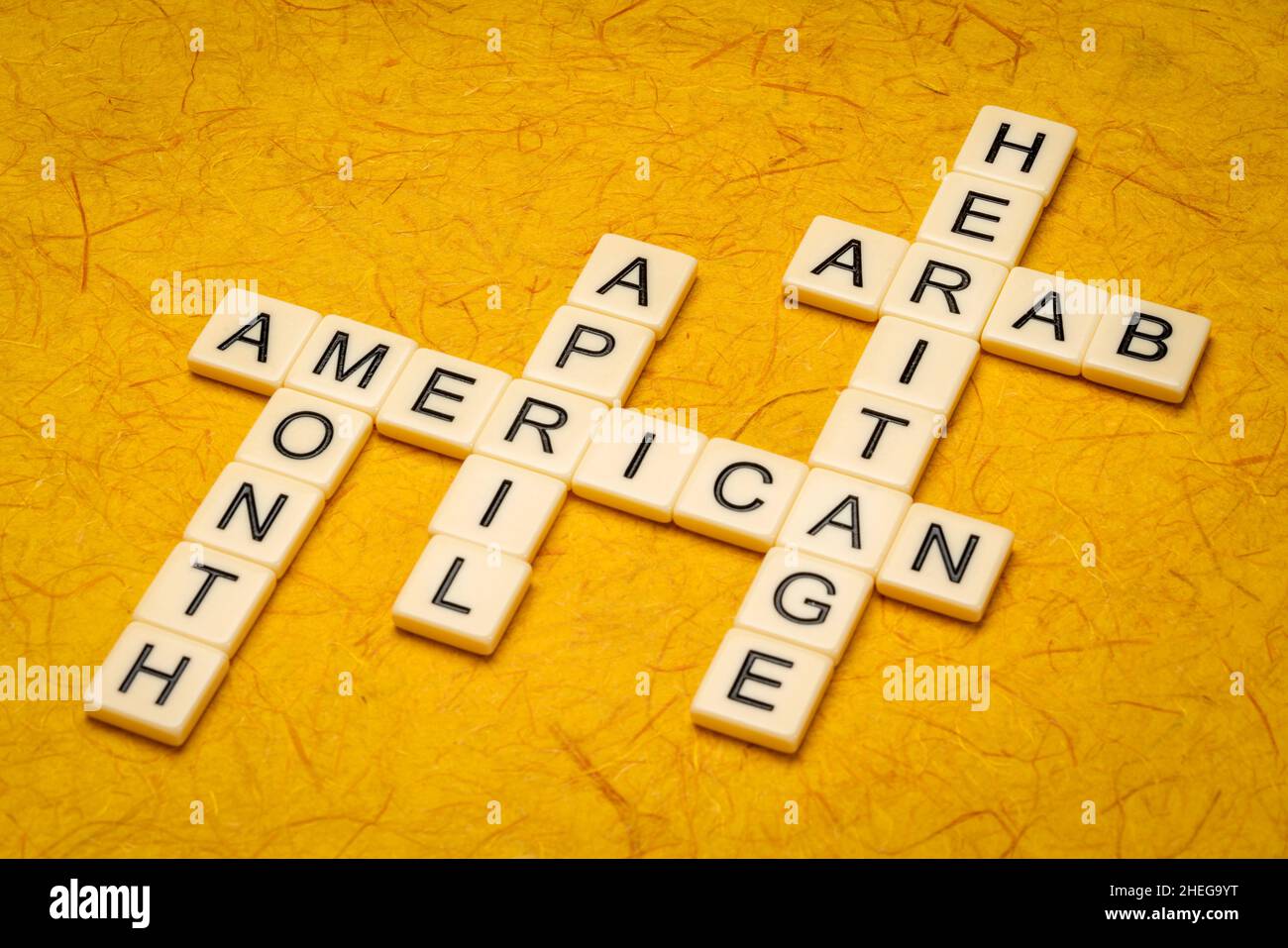April - Arab American Heritage Month, Kreuzworträtsel in Elfenbein-Buchstabenkacheln gegen strukturiertes handgefertigtes Papier Stockfoto