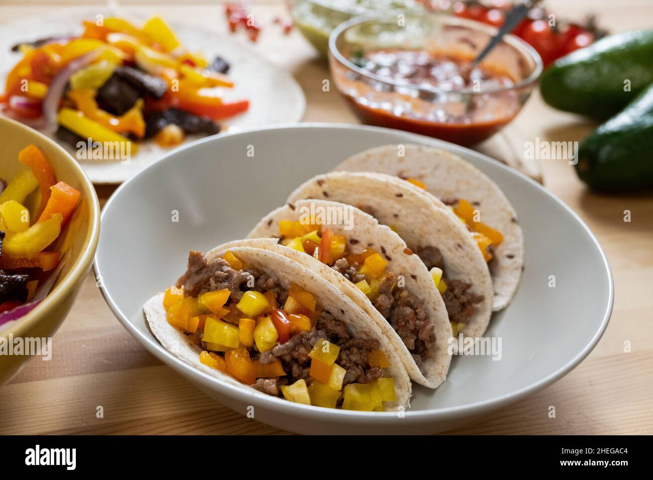 Teil des servierten Tisches mit leckeren hausgemachten mexikanischen Taco, Gemüseeintopf und herzhafter Sauce zum Abendessen vorbereitet Stockfoto