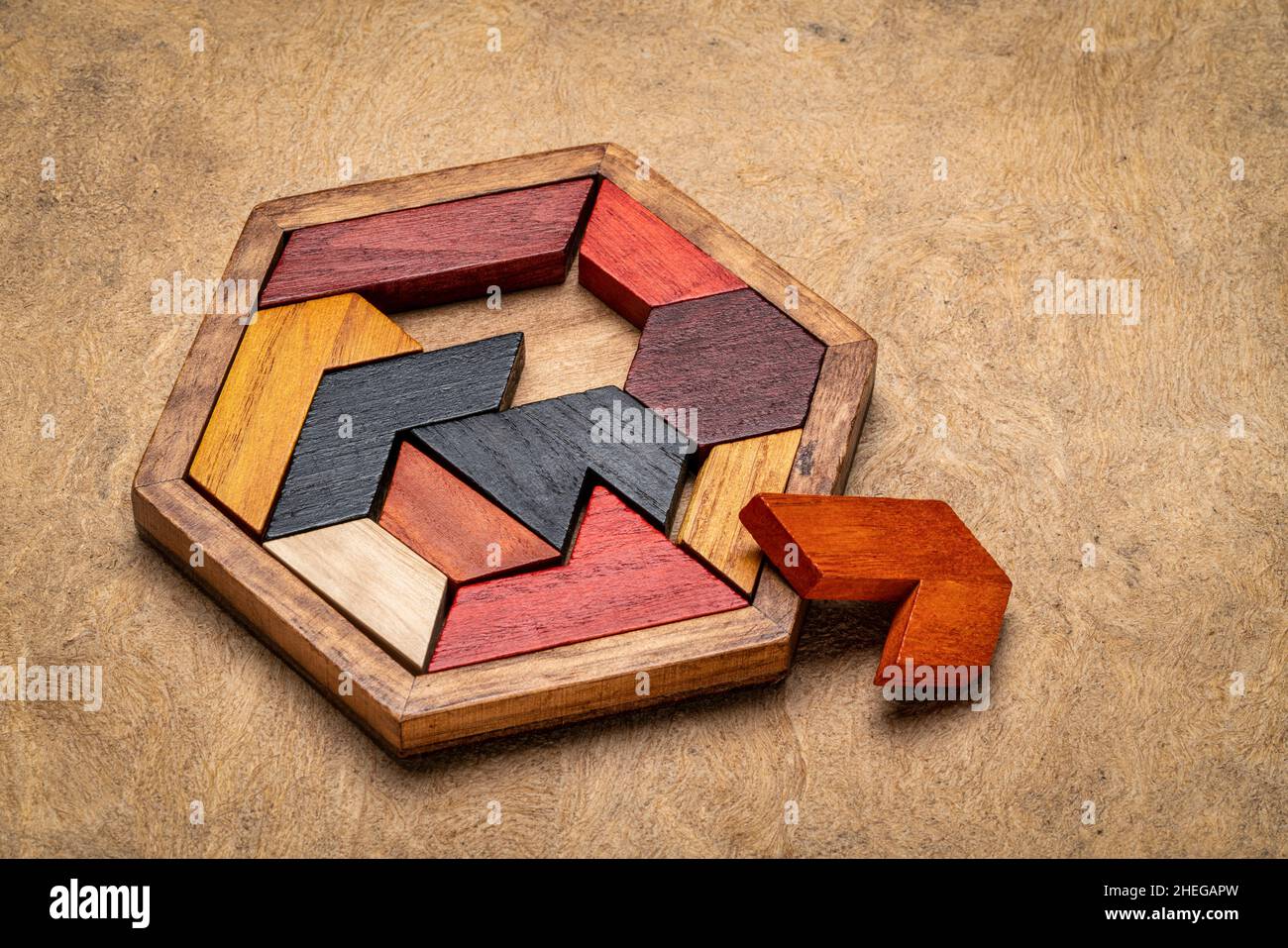 Holzhexagon Tangram Puzzle gegen strukturierte handgemachte Rindenpapier, Gehirn Teaser und lustiges Spiel mit mehreren Möglichkeiten zu lösen Stockfoto