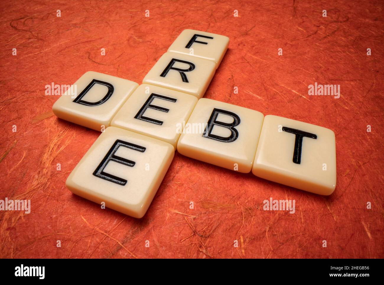 Schuldenfreies Kreuzworträtsel in Elfenbein Buchstaben Fliesen gegen texturiertes handgemachtes Papier, Finanzkonzept Stockfoto