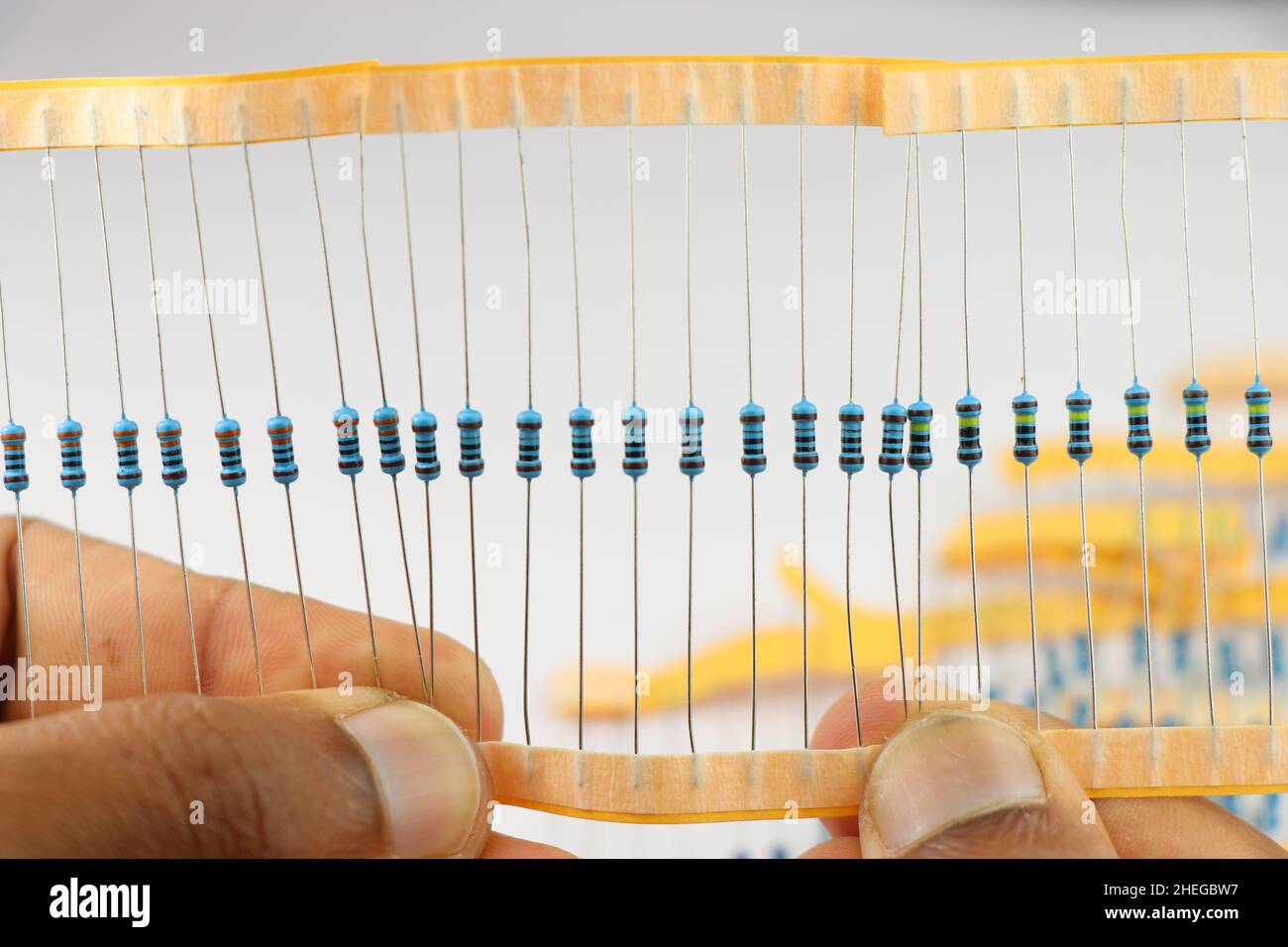 Ein Satz Widerstand, ein elektronisches Bauteil, das vor dem weißen Hintergrund in der Hand gehalten wird Stockfoto