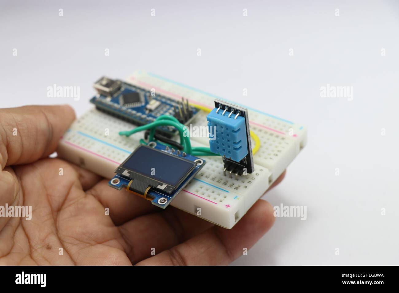 Feuchtigkeits- und Temperaturmessmodul für Arduino-Projekte mit OLED-Schaltung auf einem in der Hand gehaltenen Breadboard, das das Konzept der kreativen Idee zeigt Stockfoto