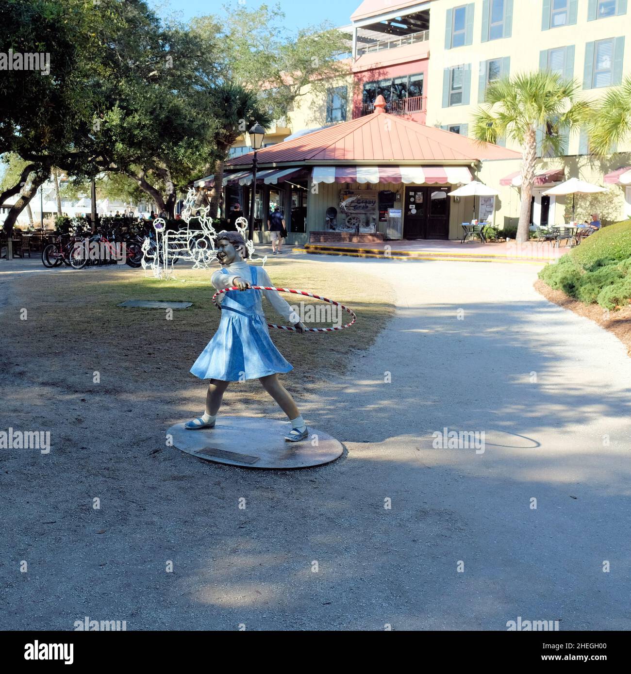 Attic Trophy Skulptur von Seward Johnson in der Hafenstadt in Hilton Head, South Carolina, USA; lebensgroße Bronzeguss-Figur eines Mädchens und eines Hula Hoop Reifen. Stockfoto