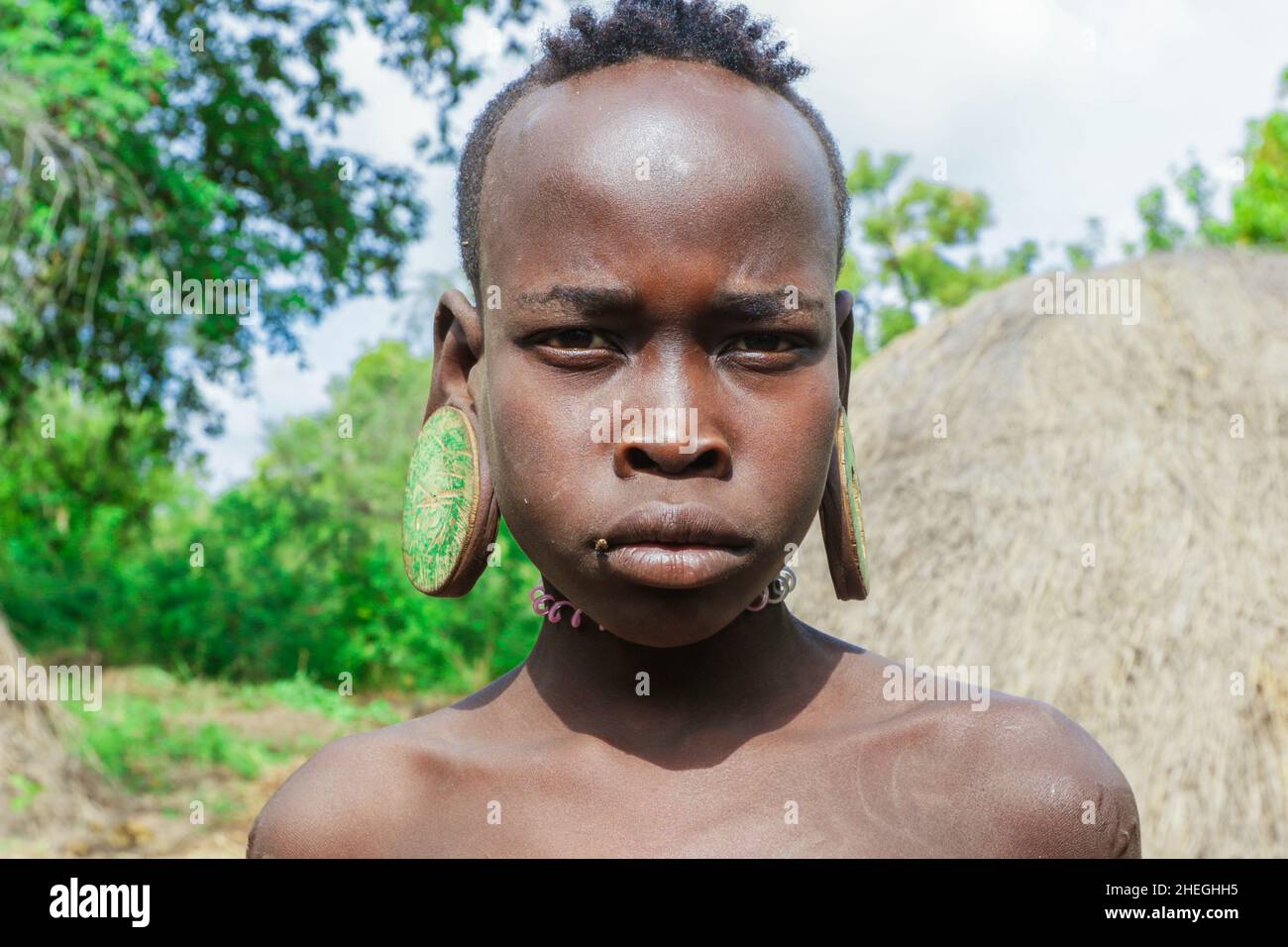 Omo River Valley, Äthiopien - 29. November 2020: Porträt eines afrikanischen Teenagers mit großen traditionellen hölzernen Ohrringen im lokalen Mursi-Stammdorf Stockfoto