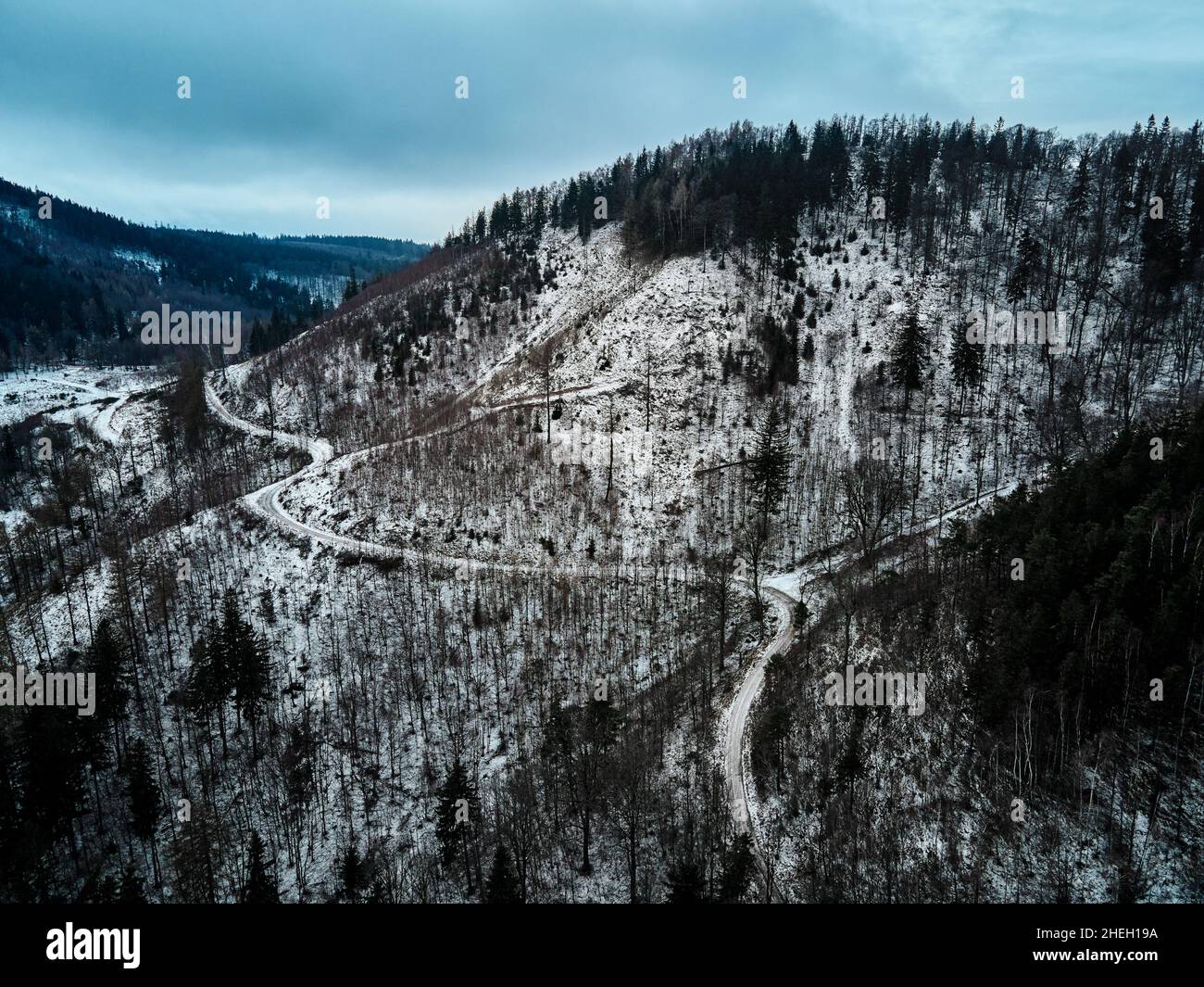 Kurvenreiche Straße durch mit Wald bedeckte Berge, Winterlandschaft mit kurviger Autobahn inmitten der Landschaft, Luftbild Stockfoto