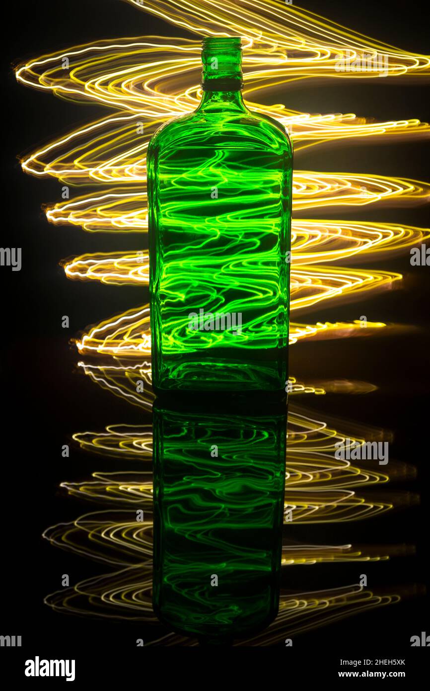 Eine grüne Flasche auf dem Hintergrund, die mit Lichtmalerei beleuchtet ist. Stockfoto