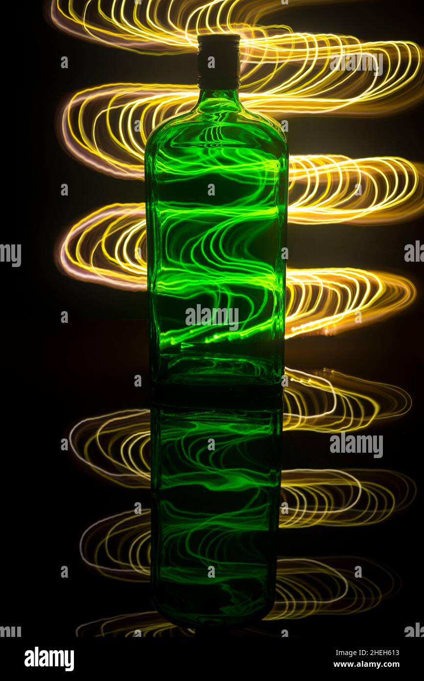 Eine grüne Flasche auf dem Hintergrund, die mit Lichtmalerei beleuchtet ist. Stockfoto
