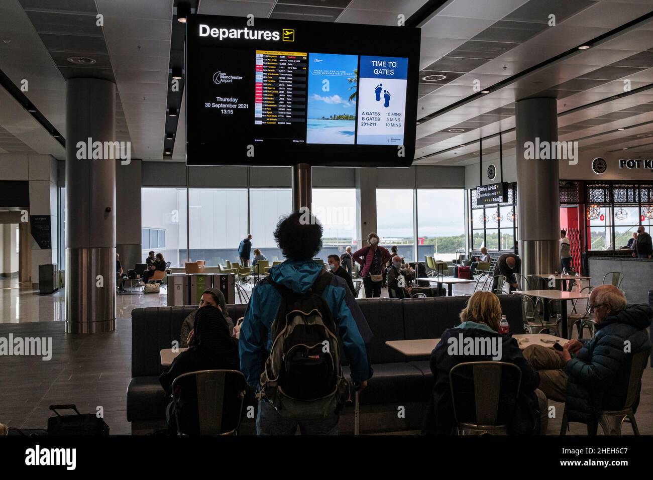 Passagier, der den Abflugsbildschirm mit den Flugzeiten in der Abflughalle des Flughafens Manchester, England, Großbritannien, betrachtet Stockfoto